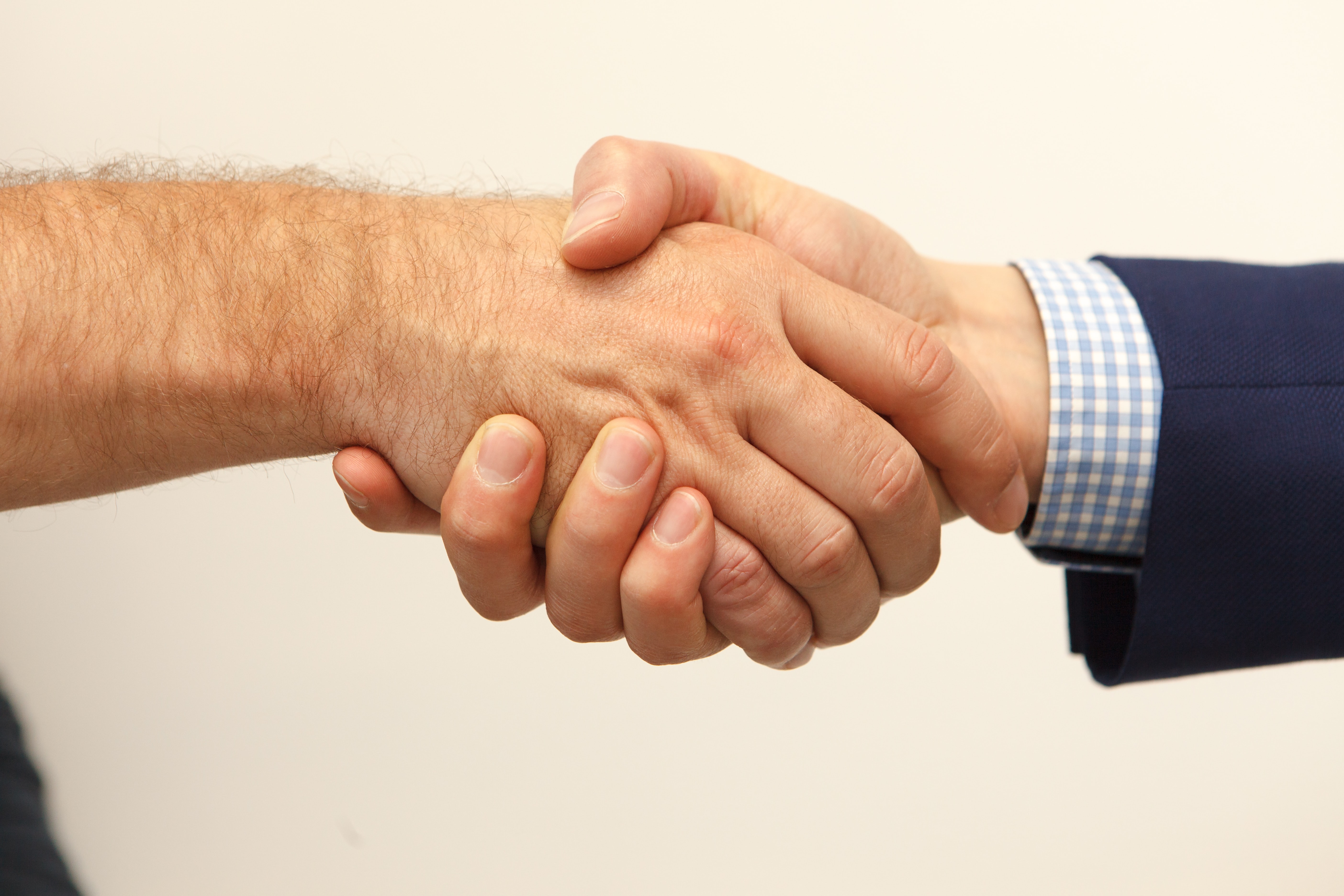 An employer's hand shakes the hand of a new employee